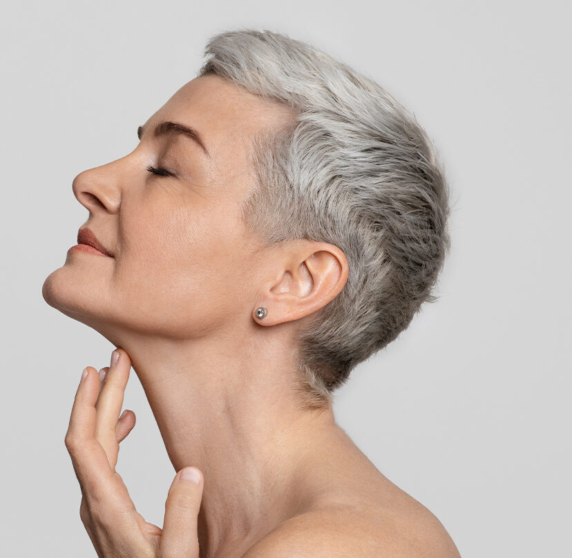Photo of an older woman with short hair touching her neckline
