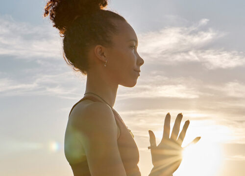 Photo of a woman in workout clothes standing outside while the sun goes down