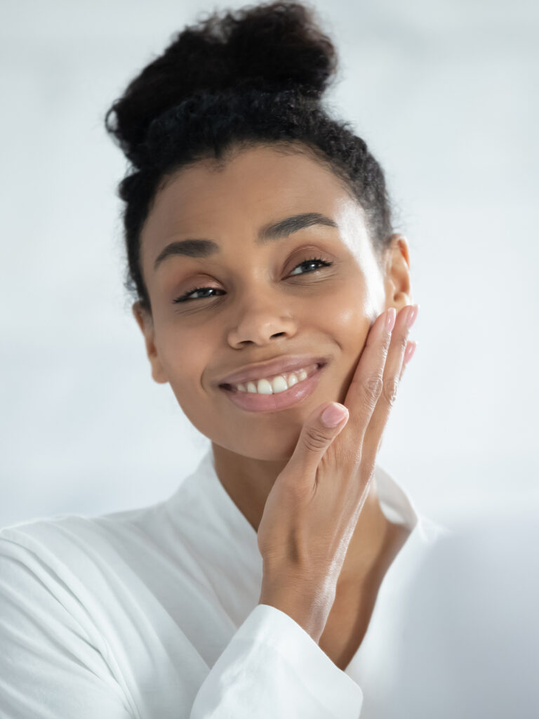 Photo of a woman with clear skin touching her cheek